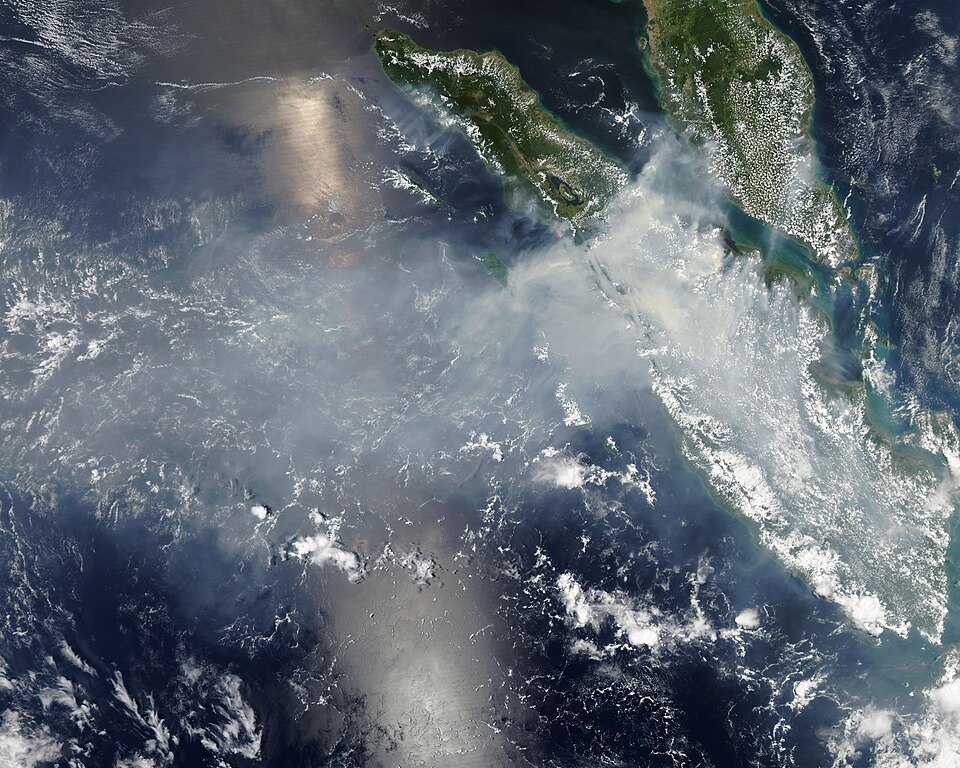 Imej satelit menunjukkan jalur asap kelabu tebal menutupi pantai timur Sumatera, dengan tanda merah kecil menandakan titik panas kebakaran